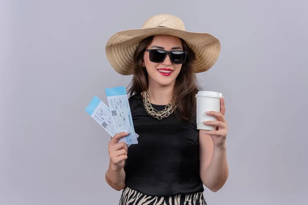 smiling traveler young girl wearing black undershirt hat wearing glasses holding tickets cup coffe white background_141793 20534 min